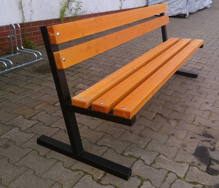 Holzbank mit Metallbeinen auf gepflastertem Gehweg