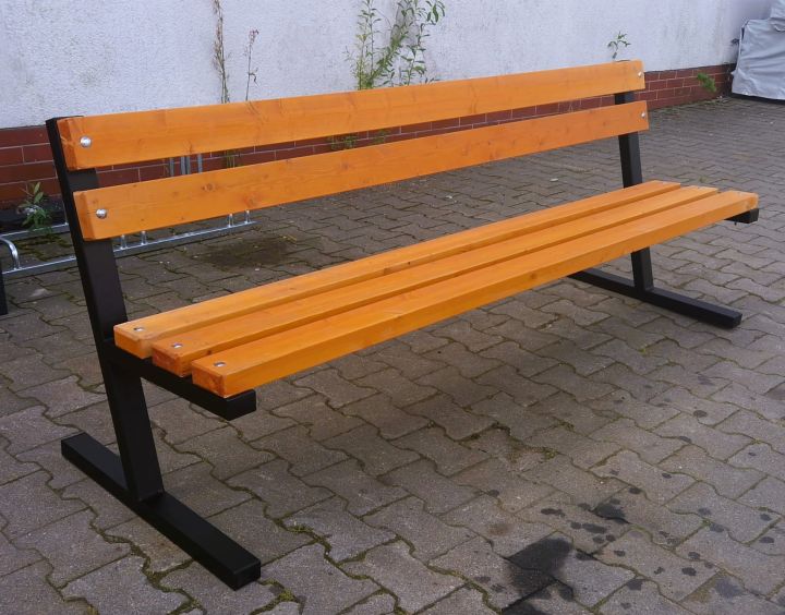 Holzbank mit Metallbeinen auf gepflastertem Gehweg