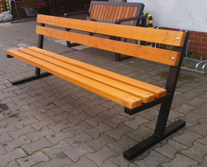 Holzbank mit Metallbeinen auf gepflastertem Gehweg